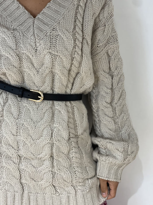 Ceinture fine en cuir noir avec boucle dorée sur pull en maille torsadée, idéale pour accentuer une silhouette élégante