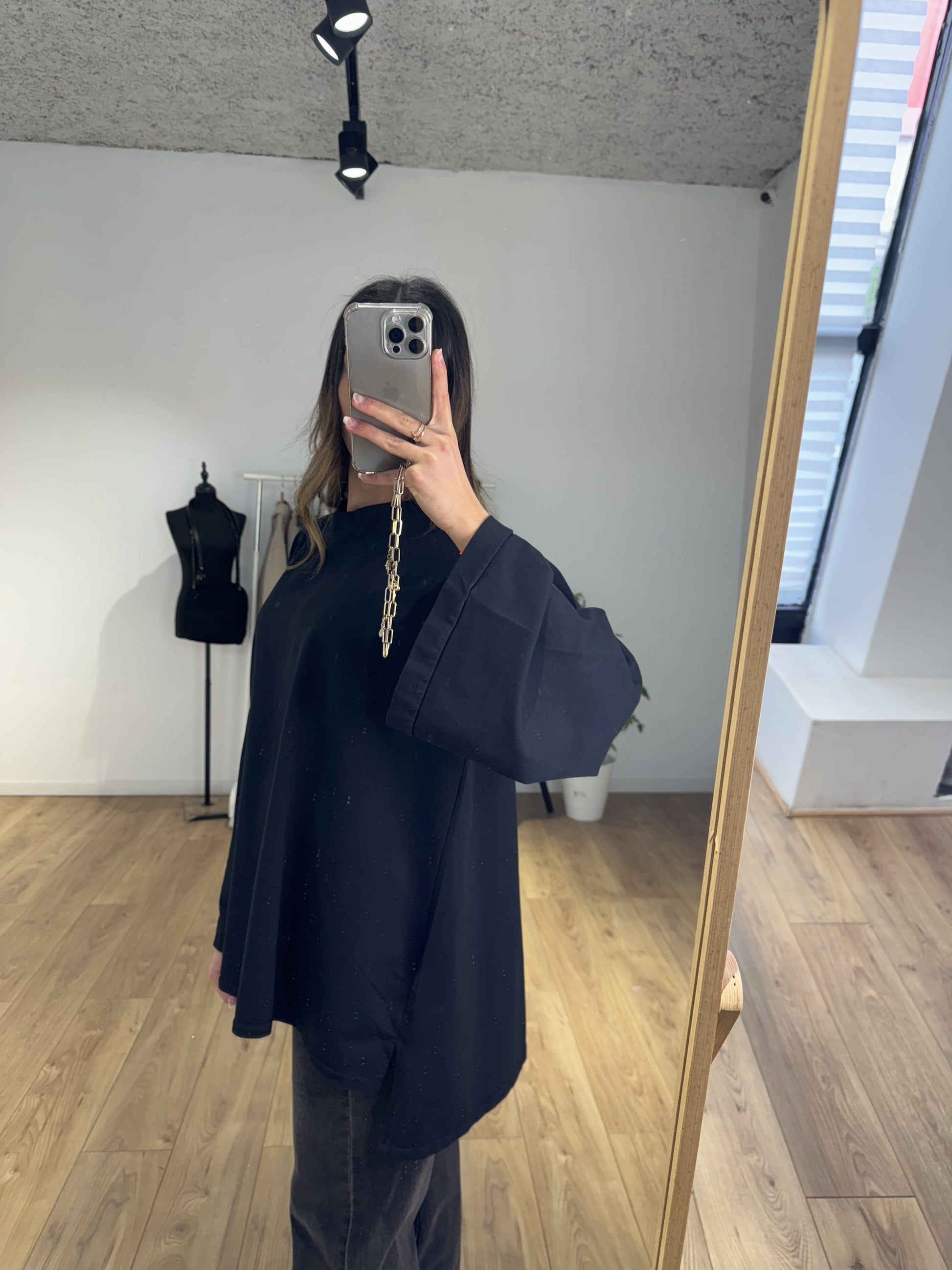 Femme portant un haut oversize noir dans un magasin