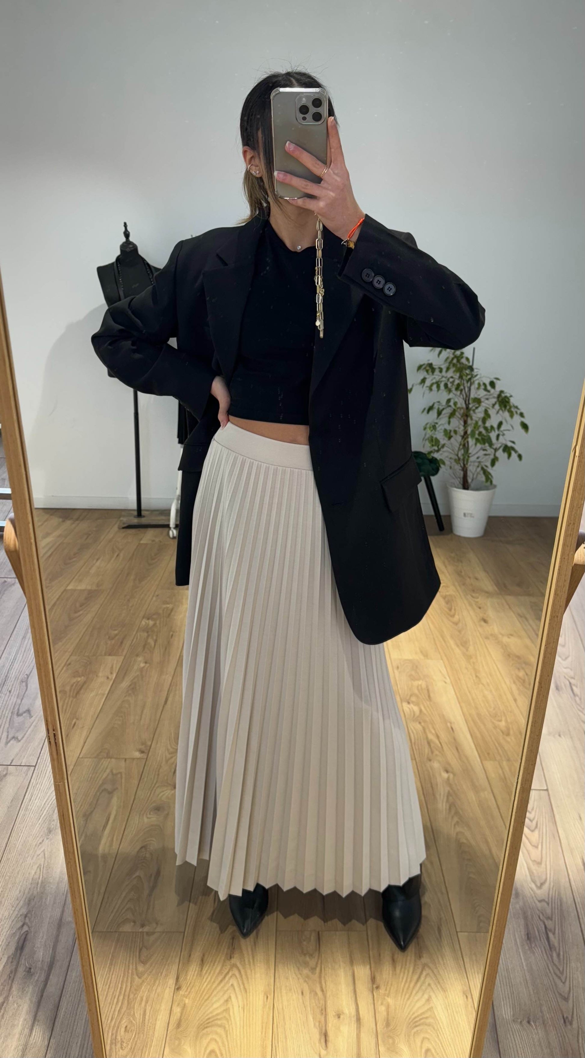 Miroir montrant jupe plissée beige avec blazer noir