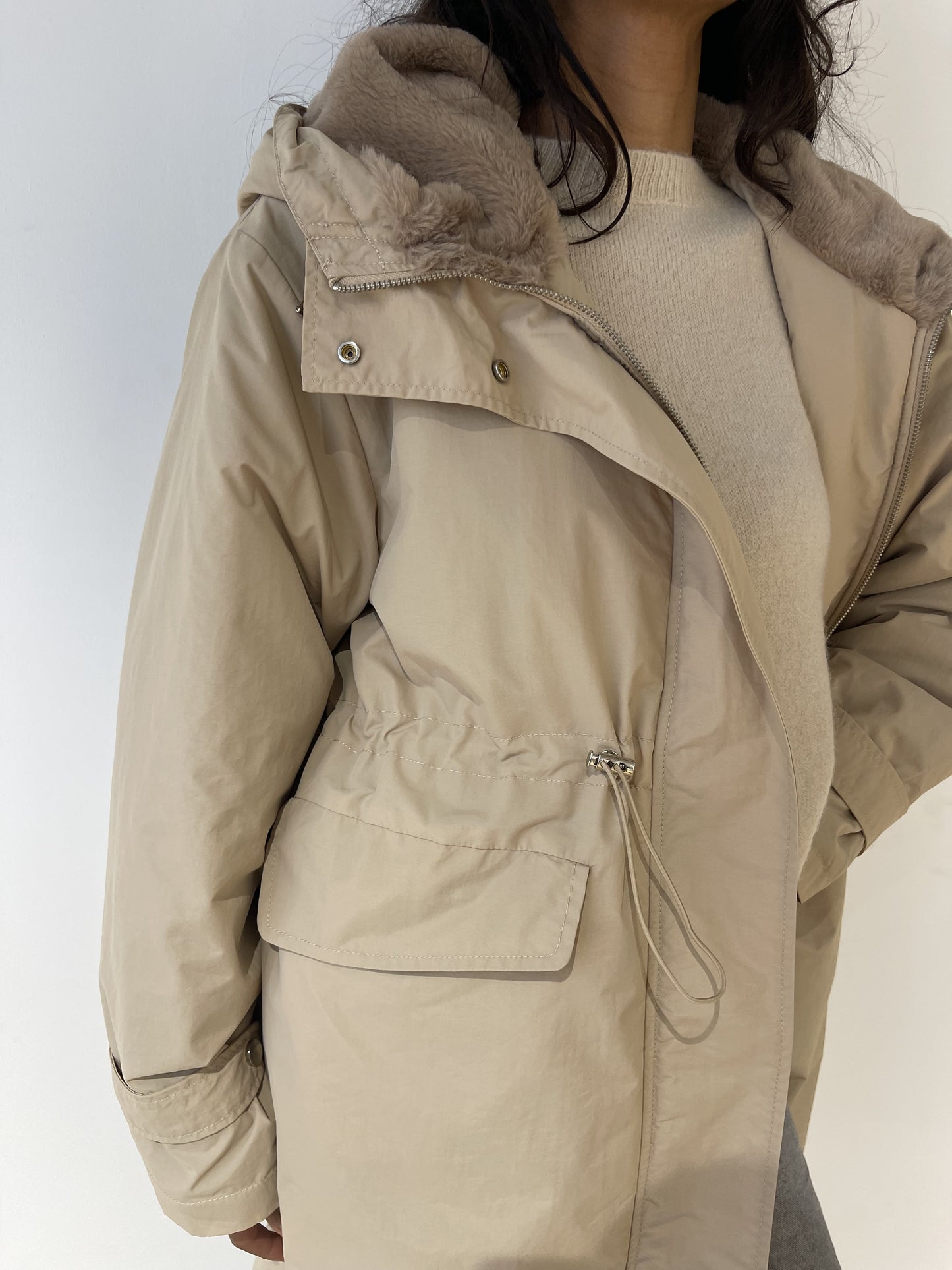 Détail du manteau beige imperméable pour femme, texture légère et coupe pratique.