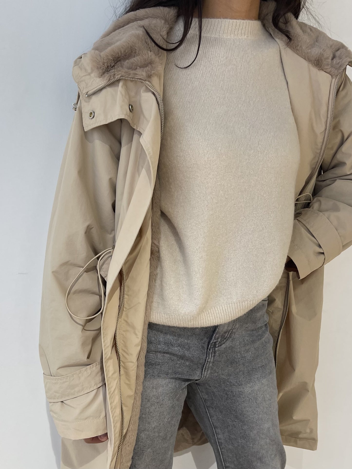 Zoom sur la capuche fourrée du manteau imperméable beige, idéale pour l’hiver.