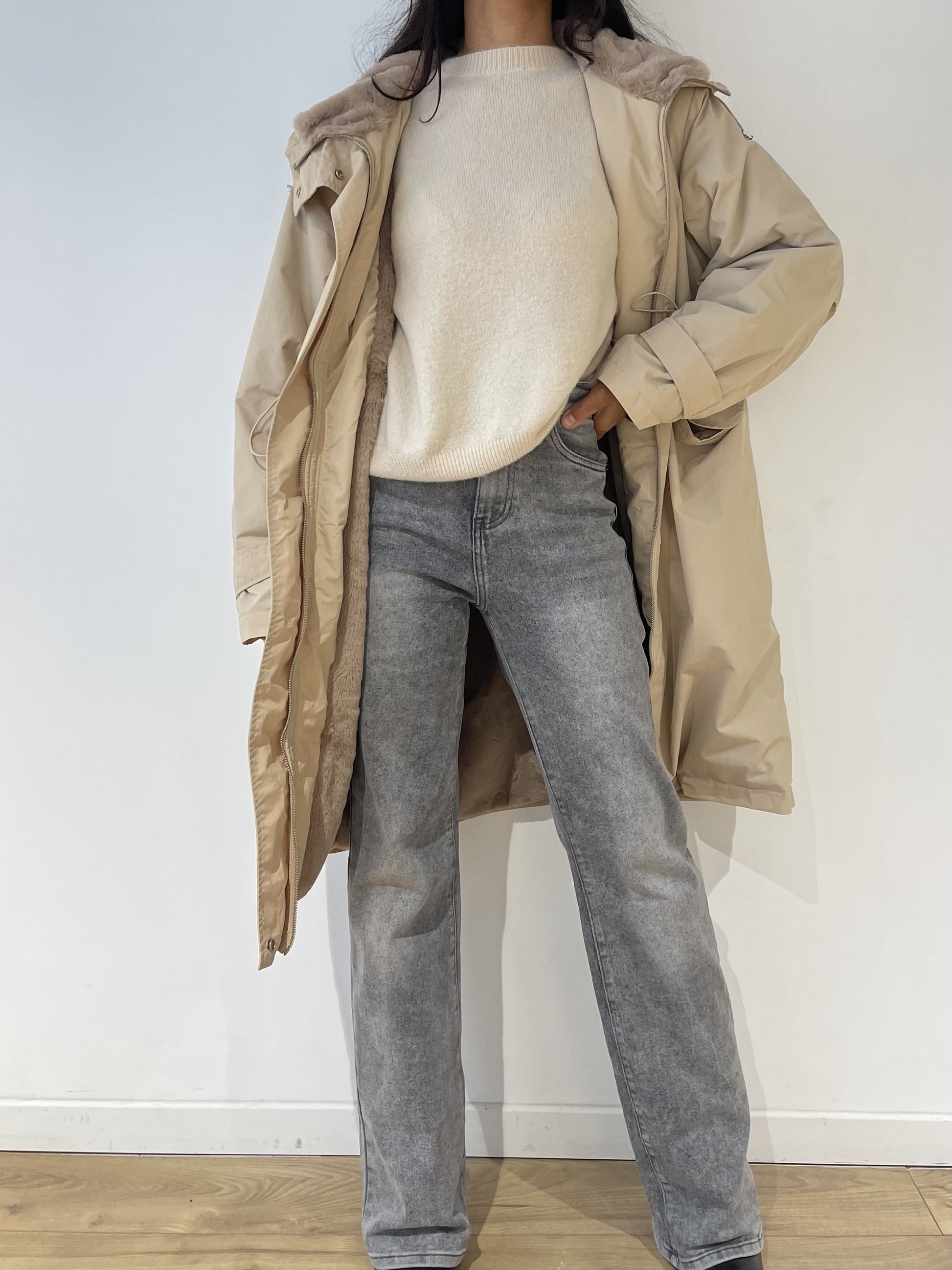 Look complet avec manteau imperméable beige pour femme, porté avec un pull crème et un jean gris.