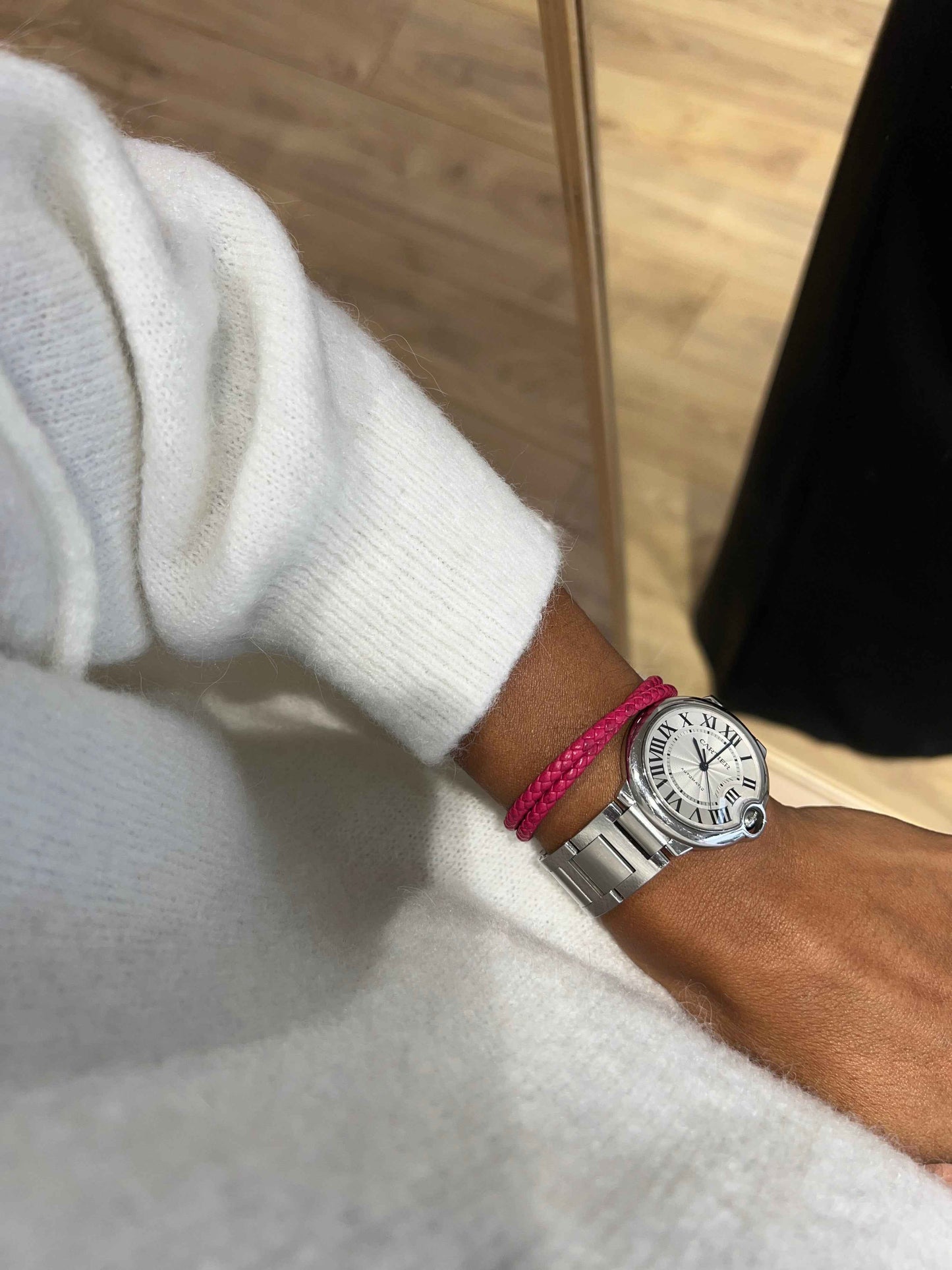 Détail du pull en laine blanc avec montre et bracelet rose.