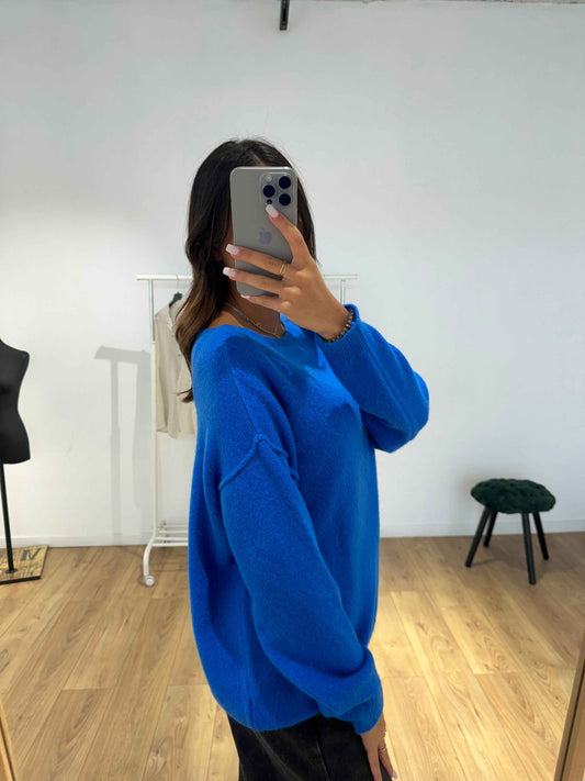 Femme prenant un selfie dans un pull en laine bleu vif, vue latérale.