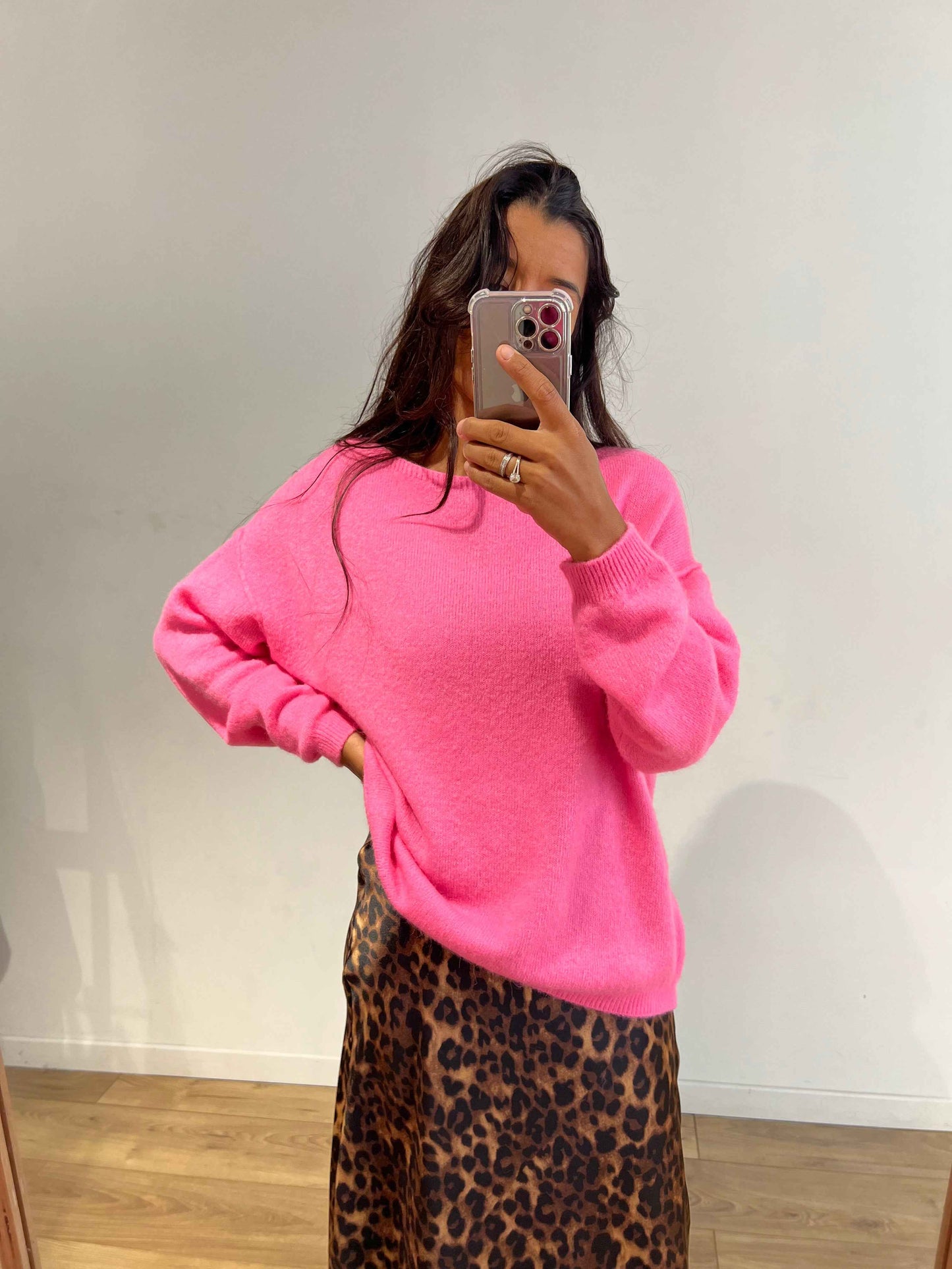 Femme portant un pull en laine rose vif avec une jupe léopard.