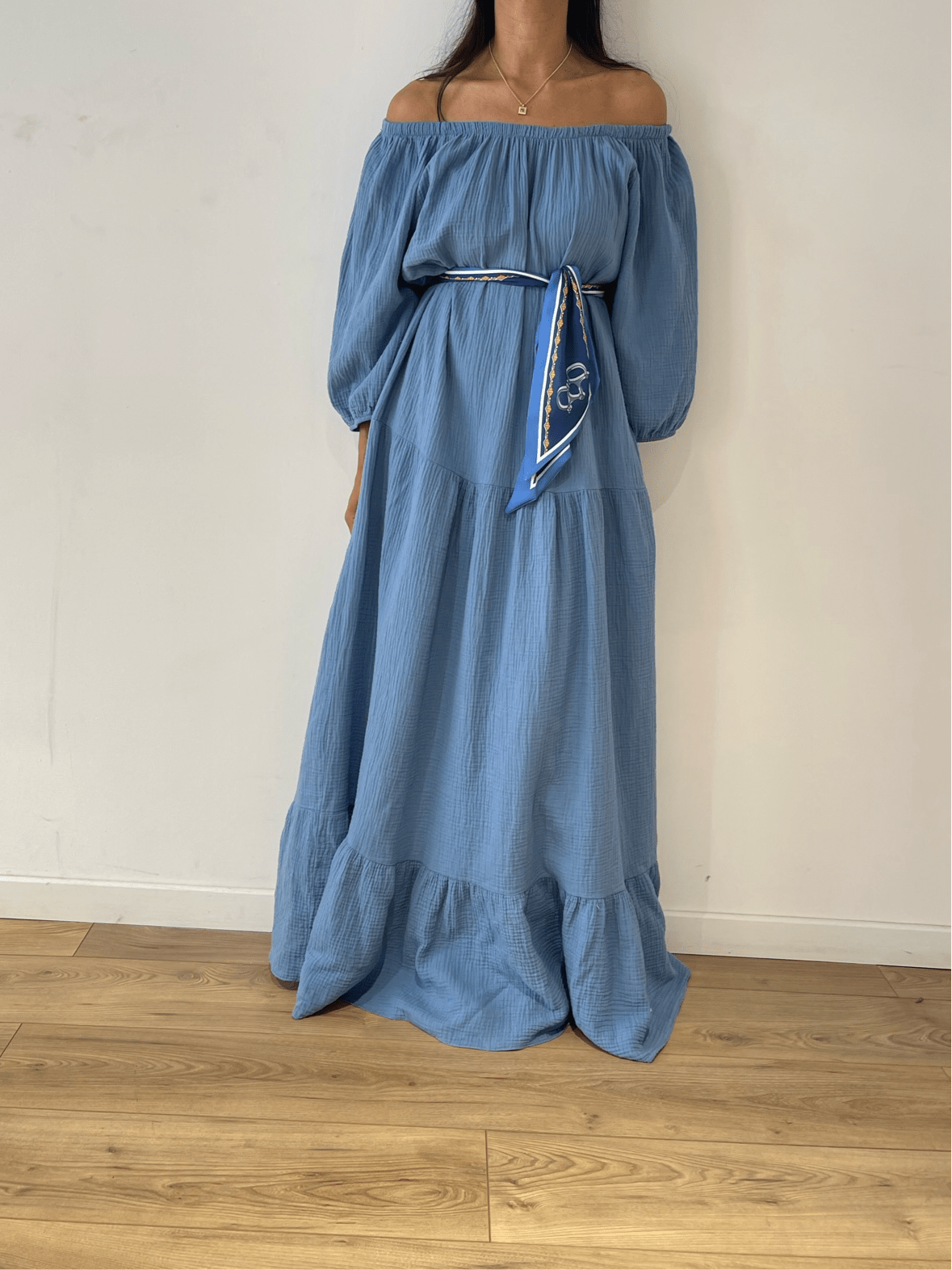 Femme portant une robe bleue en gaze de coton avec épaules dénudées et ceinture décorative