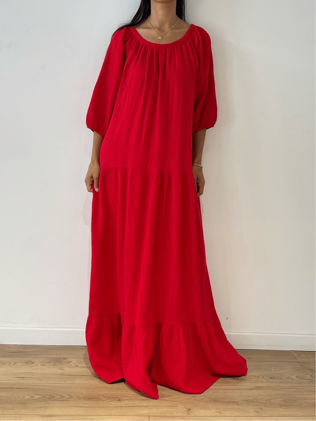 Femme portant une robe rouge en gaze de coton avec manches longues et coupe fluide.